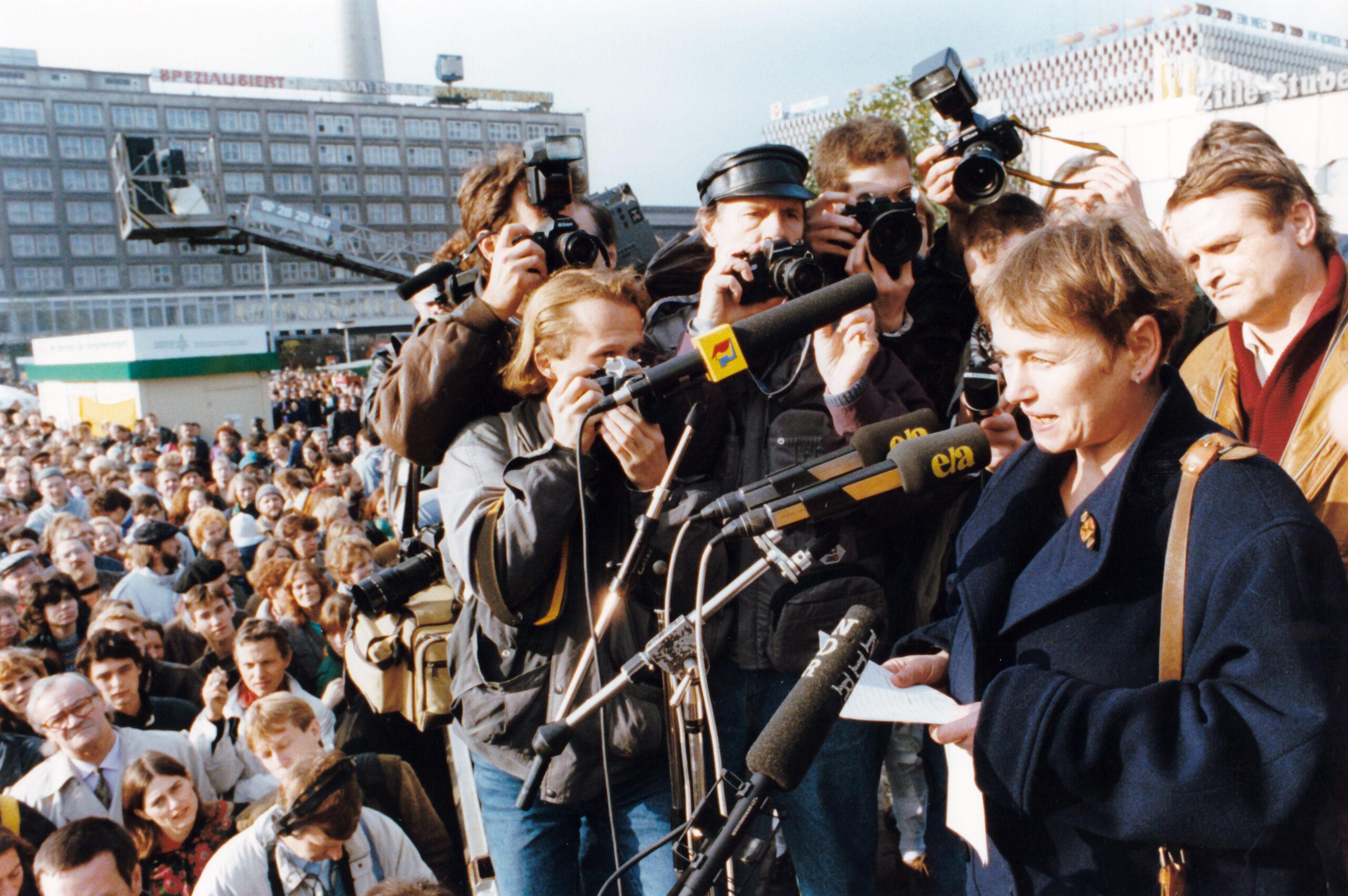 Die Bürgerrechtskämpferin Bärbel Bohley spricht am 04.11.1990 auf der Kundgebung zur Erinnerung an den 4. November 1989. Es ist noch da, das Volk der ehemaligen DDR. Zwar waren dem Aufruf von Bürgerinitiativen aus dem Ostteil der Stadt nicht wie vor einem Jahr rund 400.000 Bürger gefolgt, aber Tausende kamen dennoch auf den Alexanderplatz, um "für gleiche soziale Rechte in Deutschland" zu demonstrieren. Zu den Mitinitiatoren der heutigen Kundgebung gehörte wiederum das Neue Forum.